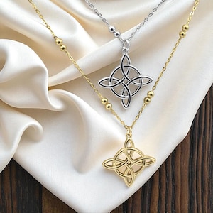 May include: Two necklaces with Celtic knot pendants. One necklace is gold-toned, the other is silver-toned. The gold necklace has a chain with small gold beads. The silver necklace has a simple chain. Both pendants have a four-pointed design.