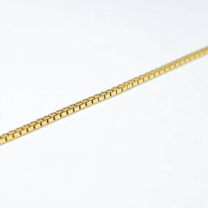 A gold chain necklace is shown against a white background.