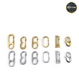 Pode incluir: Uma coleção de doze clipes de mola metálicos dispostos em duas filas de seis, com acabamentos em dourado e prateado. O conjunto inclui várias formas como ovais, retangulares e em gota, cada uma equipada com um fecho de mola funcional.