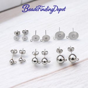 Puede incluir: Una colección de componentes de pendientes de acero inoxidable, que incluyen almohadillas planas con bucles y pendientes de bola de varios tamaños. La imagen está sobre una superficie de madera blanca. El texto "BeadsFindingDepot" es visible.