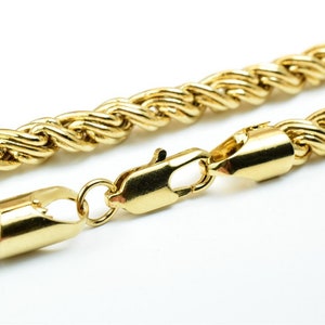 May include: A gold rope chain necklace with a lobster clasp closure.