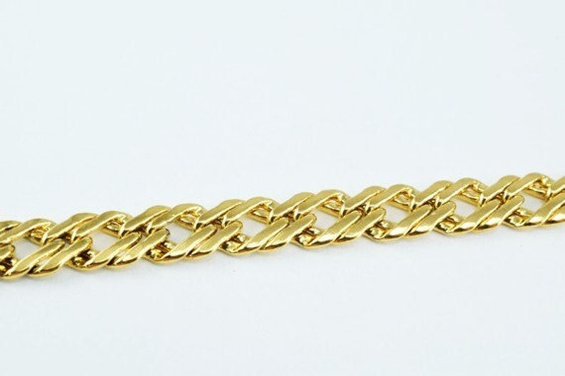 Puede incluir: Un brazalete de cadena dorada con un dise&ntilde;o de eslabones curb.