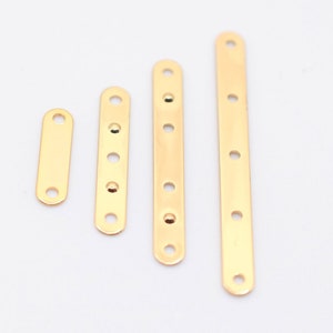 May include: Four gold-colored metal connector bars of varying lengths, each with evenly spaced holes for screws or fasteners. The bars are arranged vertically against a white background, showcasing their polished, reflective surface. These are likely used in jewelry making or small craft projects.