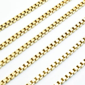A close-up image of several gold-colored metal chains arranged in a repeating pattern.
