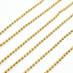 May include: Gold ball chain, a type of jewelry chain made of small, round beads connected together. The chain is shown in a straight line, with multiple strands laid out parallel to each other.