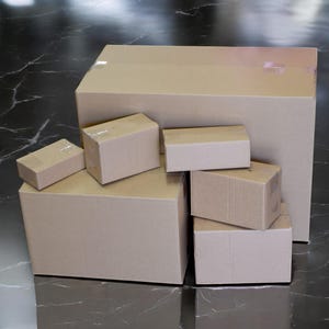 K&ouml;nnte beinhalten: Ein Stapel aus sechs braunen Pappkartons in verschiedenen Gr&ouml;&szlig;en. Die Kartons sind in Pyramidenform angeordnet, wobei der gr&ouml;&szlig;te Karton unten und der kleinste Karton oben liegt.