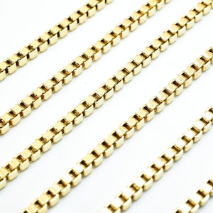 A collection of gold-colored metal chains arranged in a diagonal line against a white background.