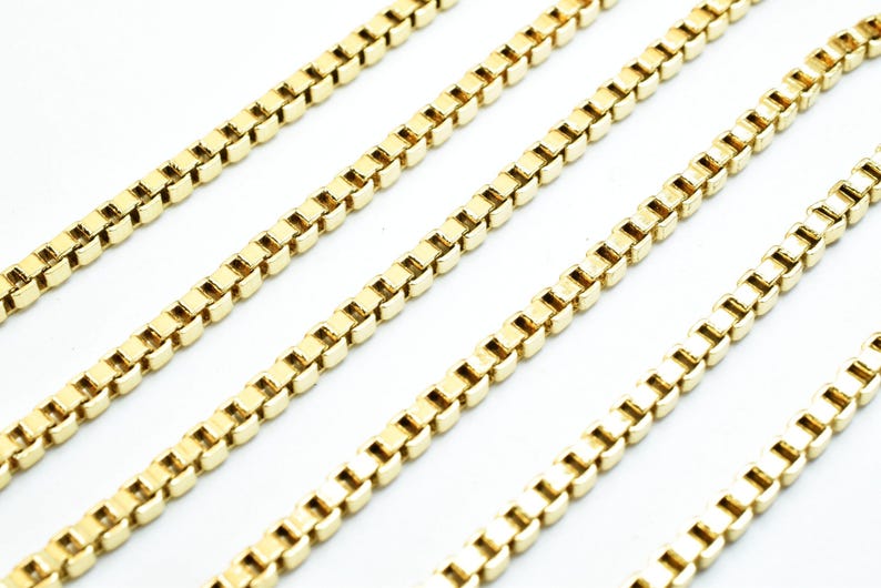 A collection of gold-colored metal chains arranged in a diagonal line against a white background.