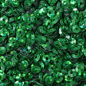 May include: A close-up view of a large quantity of green iridescent sequins. The sequins are round with a hole in the center.