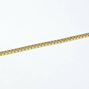A gold-colored necklace chain is shown against a white background.