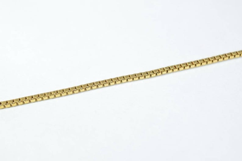 A gold-colored necklace chain is shown against a white background.