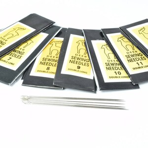 Może przedstawiać: Zestaw 7 czarnych i ż&oacute;łtych opakowań igieł do szycia z ilustracją jelenia na każdym opakowaniu. Opakowania są oznaczone "DEER SEWING NEEDLES" z numerem od 6 do 12. Igły są podw&oacute;jnie długie.