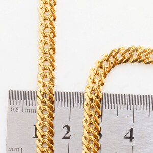 Puede incluir: Primer plano de una cadena de oro medida con una regla. La cadena tiene 2 cm de ancho.
