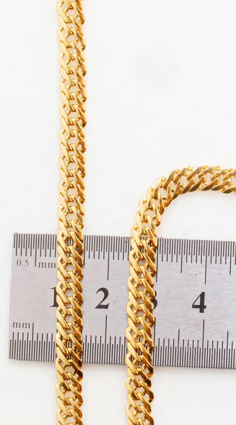 Puede incluir: Primer plano de una cadena de oro medida con una regla. La cadena tiene 2 cm de ancho.