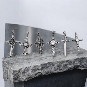 May include: Six silver cross pendants with intricate designs. Some feature a clear stone in the center.