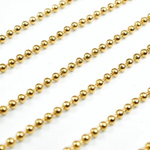 May include: A close-up of a gold ball chain. The chain is made of small, round beads that are linked together.