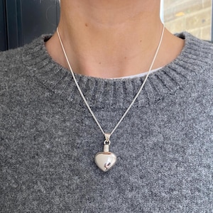 Puede incluir: Un collar de plata con un colgante en forma de coraz&oacute;n. El colgante es un peque&ntilde;o coraz&oacute;n hueco que cuelga de una delicada cadena de plata.
