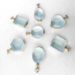 Puede incluir: Siete colgantes de locket antiguos de diferentes formas y tamaños. Los lockets están hechos de metal dorado y tienen tapas de vidrio transparente. Los lockets están todos cerrados y tienen un diseño delicado.