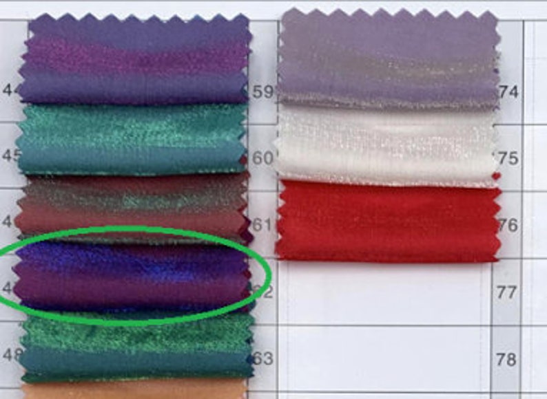 May include: Swatch card with a variety of fabric samples in different colors and textures. The card is numbered with rows and columns. The fabric samples are arranged in a grid pattern. The fabric sample in the third row and first column is a deep purple color with a slight sheen.