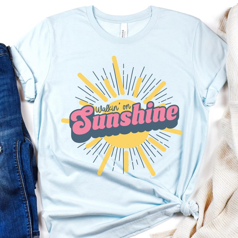 May include: Light blue t-shirt with a retro-style graphic of a sun with rays and the text "Walkin' on Sunshine".