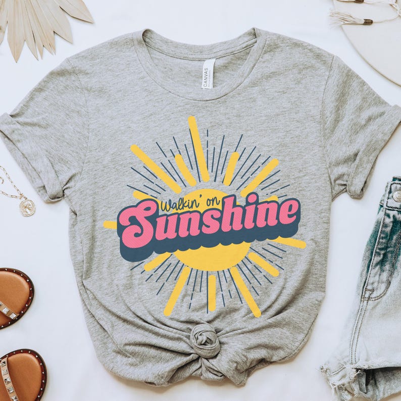 May include: A gray t-shirt with a yellow sun and the text "Walkin' on Sunshine" in pink and blue letters.