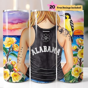 May include: A stainless steel tumbler with a colorful watercolor design featuring a woman with a tattoo on her arm, a bird, and flowers. The tumbler has the word "ALABAMA" printed on it.