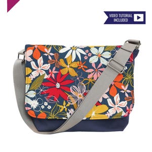 May include: A floral messenger bag with a gray strap and a navy blue base. The bag has a floral print with red, yellow, and white flowers on a dark blue background. The text "Crosscut Sewing Co." and "Video Tutorial Included" is visible on the image.