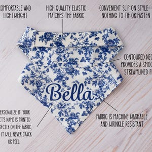 May include: A white and blue floral patterned dog bandana with the name "Bella" in navy blue script. The bandana is lightweight, machine washable, and wrinkle-resistant. It has a contoured neck for a smooth fit and a convenient slip-on style.
