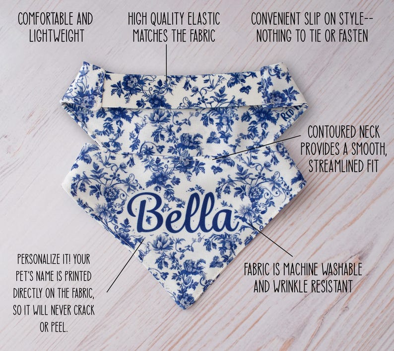 May include: A white and blue floral patterned dog bandana with the name "Bella" in navy blue script. The bandana is lightweight, machine washable, and wrinkle-resistant. It has a contoured neck for a smooth fit and a convenient slip-on style.