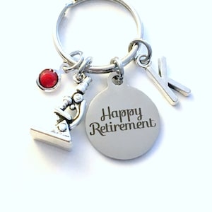 May include: Silver keychain with a red gem, a microscope charm, and a tag that says "Happy Retirement".