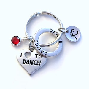 May include: Silver keyring with a heart charm that says "I love to dance!" and a round charm that says "Dance". There is also a small red gem and a round charm with the letter "K" on it.