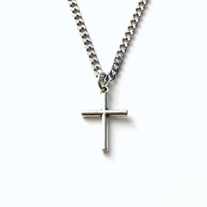May include: A silver chain necklace with a small silver cross pendant.