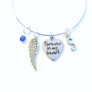 May include: Silver charm bracelet with a heart charm that says "Forever in my heart", an angel wing charm, a blue gemstone charm, and a letter "S" charm.