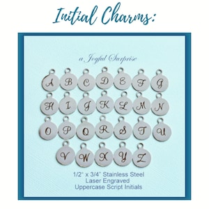 May include: A collection of twenty-six circular silver-toned metal charms, each featuring a single laser-engraved uppercase letter in a script font. The text reads Initial Charms, a Joyful Surprise, and 1/2 inch x 3/4 inch Stainless Steel.