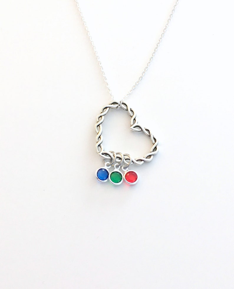 May include: A silver necklace with a twisted heart pendant and three dangling charms. The charms are blue, green, and red.