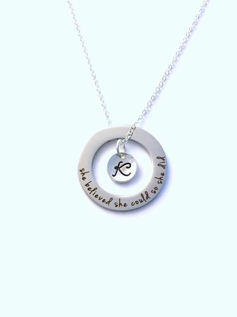 May include: Silver necklace with a round pendant that says "she believed she could so she did" and a small charm with the letter K in the center.