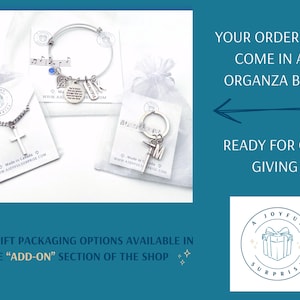 May include: A collection of jewelry and accessories, including a cross necklace, a bracelet with charms, and a keychain, presented in organza bags. The image includes text that says "Ready for gift giving."