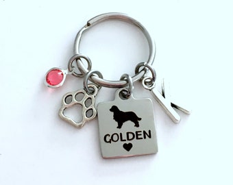 May include: Silver keychain with a paw print charm, a red rhinestone, a charm with a silhouette of a golden retriever and the word "GOLDEN" with a heart, and a letter "K" charm.