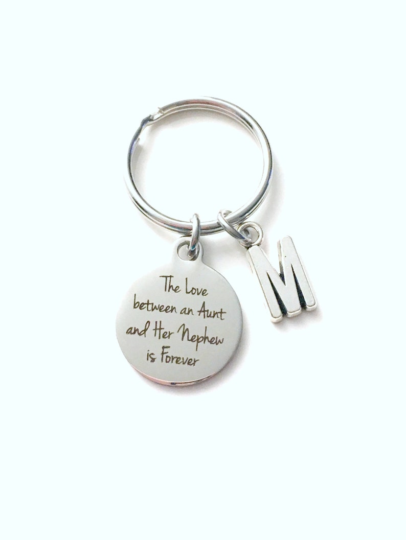 May include: Silver keychain with a round charm that says "The Love between an Aunt and Her Nephew is Forever". A silver charm with the letter "M" is attached to the keychain.