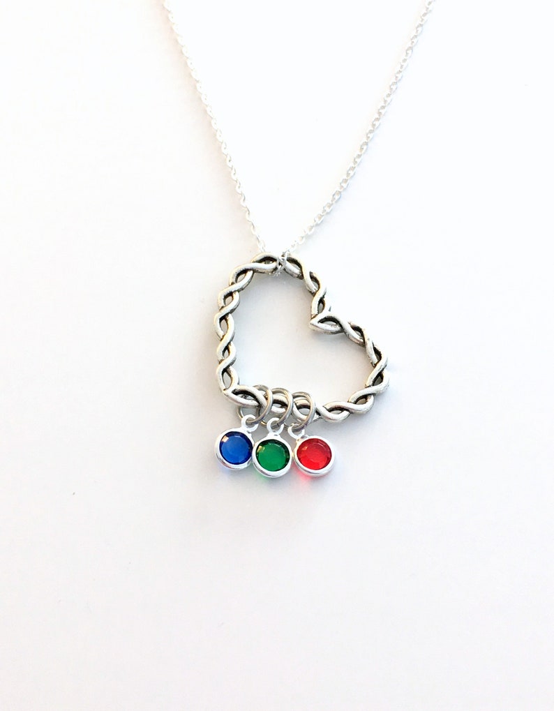 May include: A silver necklace with a braided heart pendant and three dangling charms with blue, green, and red gemstones.