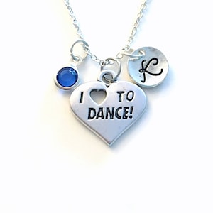 May include: Silver necklace with a heart charm that says "I heart to dance!" and a blue crystal charm. The necklace also has a silver charm with the letter "K" on it.