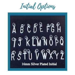 May include: A collection of silver-plated initial charms, each 16mm in size, displayed against a dark blue background. The letters A through Z are shown, with a looped design at the top of each letter. The text "Initial Options" is at the top.