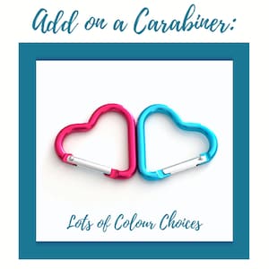 May include: Two heart-shaped carabiners, one in bright pink and one in light blue, each featuring a silver-colored spring-loaded gate. The image includes the text Add on a Carabiner: at the top and Lots of Colour Choices at the bottom.