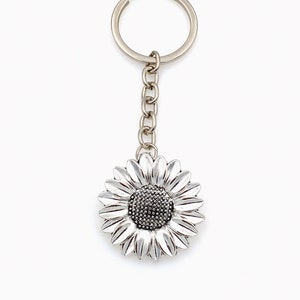 May include: Silver sunflower keyring with a silver chain and a silver key ring.