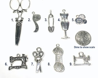 May include: Nine silver-toned metal charms with sewing-themed designs. The charms include scissors, a tape measure, a safety pin, a dress form, buttons, a sewing machine, yarn, and a dime for scale.