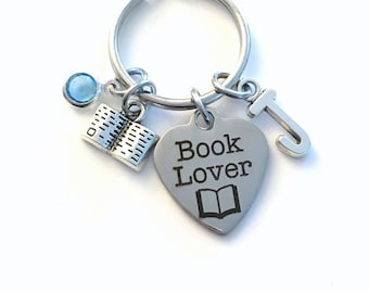 Puede incluir: Llavero de corazón plateado con las palabras "Book Lover" y un pequeño icono de libro. El llavero también incluye un pequeño dije de libro plateado, un dije de letra "J" plateado y un dije de cristal azul claro.