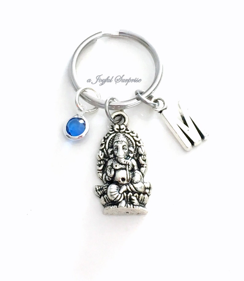 May include: Silver keychain with a blue crystal charm, a silver letter M charm, and a silver charm of the Hindu deity Ganesha.