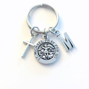 May include: Silver keyring with a St. Michael medal, a cross charm, and a letter 'M' charm. The medal features an image of St. Michael slaying a dragon and the words 'St. Michael Pray For Us'.