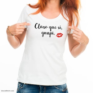 May include: White t-shirt with black text that reads "Claro que sí, guapi." and a red lipstick kiss mark.