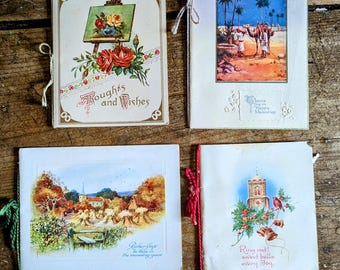 May include: Four vintage greeting cards with illustrations and text. One card features a painting of roses and the words "Thoughts and Wishes." Another depicts a desert scene with camels. The third shows a rural landscape, and the last has a church and the words "Ring out! sweet bells every day."